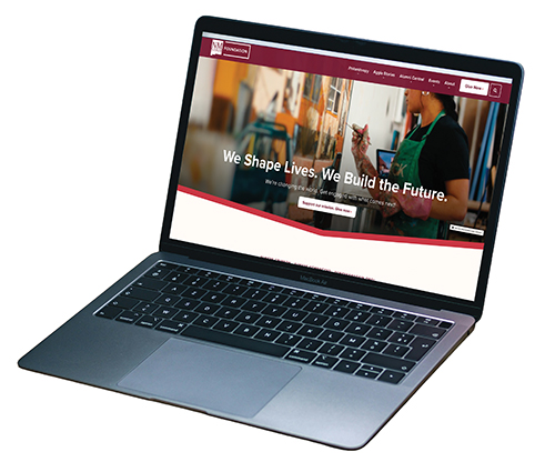 Laptop displaying a university website homepage with the headline 'We Shape Lives. We Build the Future.'