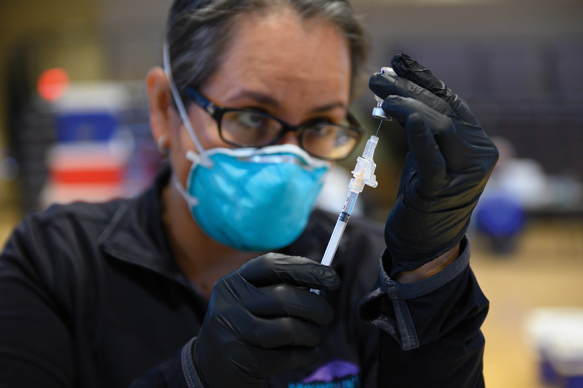 A woman prepares a vaccine dose. 
