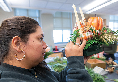 Cristina Benitez creates a Thanksgiving centerpiece during a floral team work session.