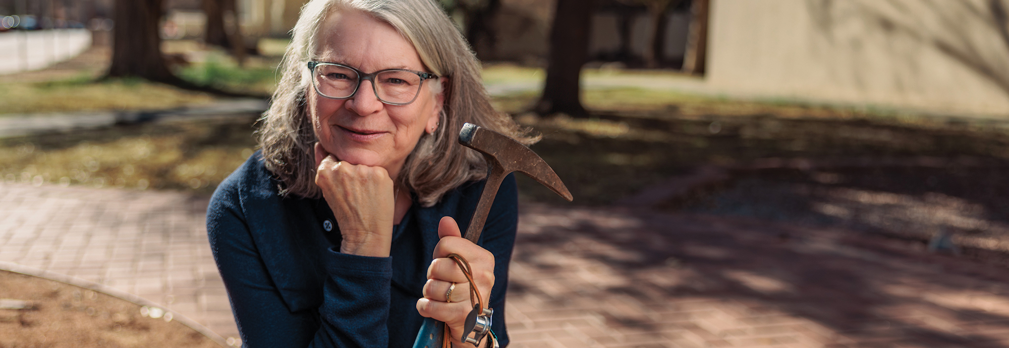 NMSU Geological Sciences Department Head Nancy McMillian holds Russ Jentgen’s loupe and pickax, which are passed among the department heads when they take office.